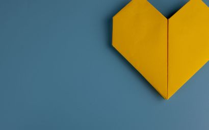 A yellow origami heart on a blue background